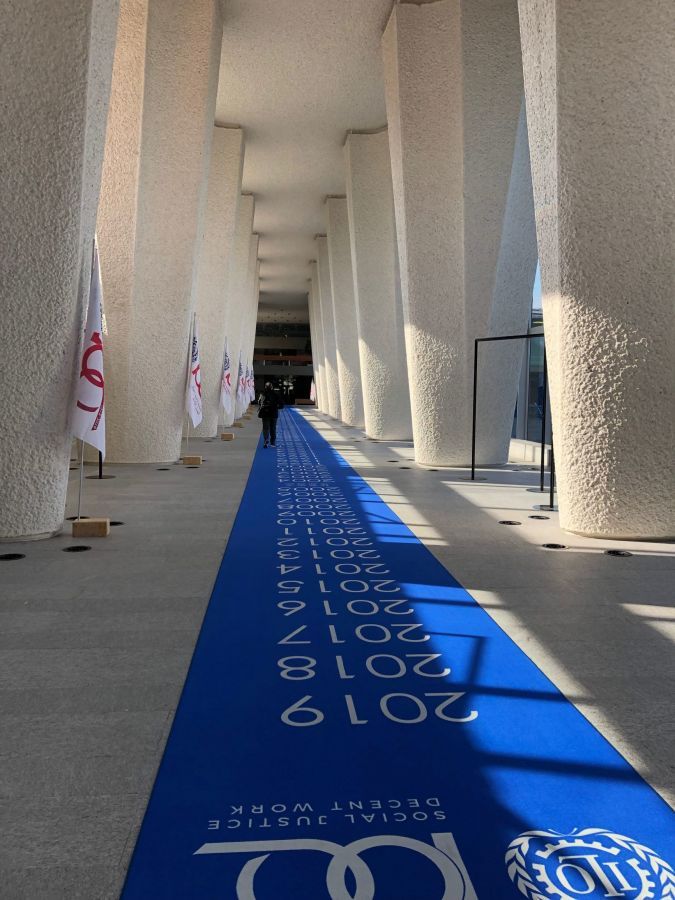 Entrance of ILO seminar in Geneva. A long blue carpet under a stone structure.